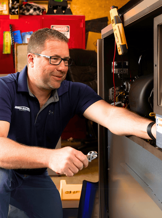 HVAC technician working on AC unit at jobsite.