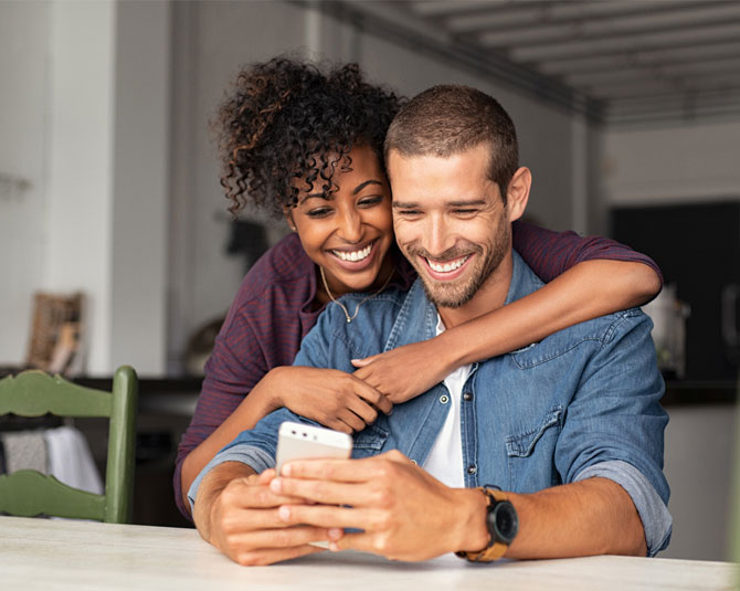 Smiling young couple looking at a smart phone.