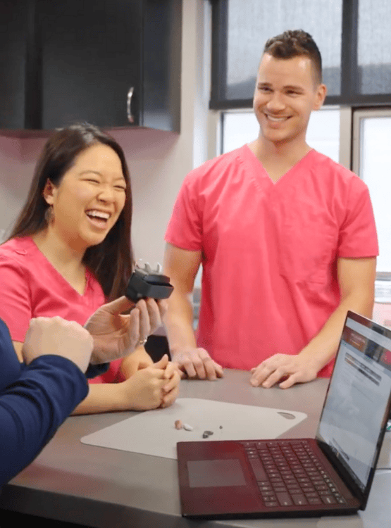 Two employees in scrubs standing at the counter laughing.