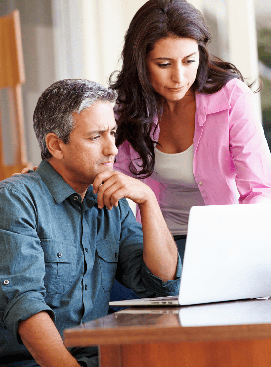 Middle-aged couple planning for retirement on their computer.