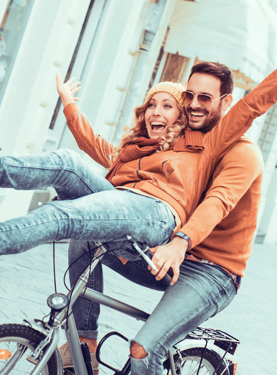 Young smiling couple riding a bicycle in Fall.