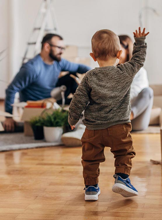 little baby taking first steps towards parents in their new home