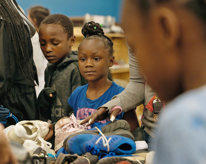 Little girl looking for shoes on a table at the Lincoln Day Without Shoes event.